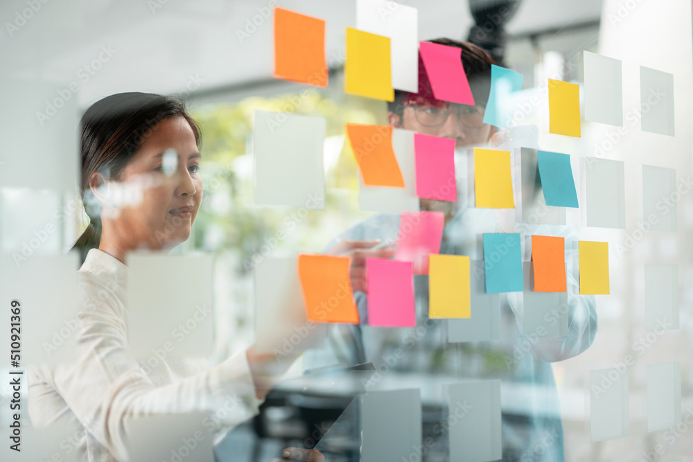 Poster two business executive team holding and taking notes keyword on board wall to brainstorm about a new