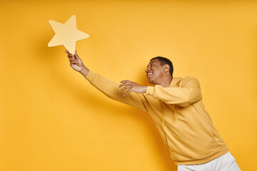 Playful mixed race man catching yellow star against yellow background
