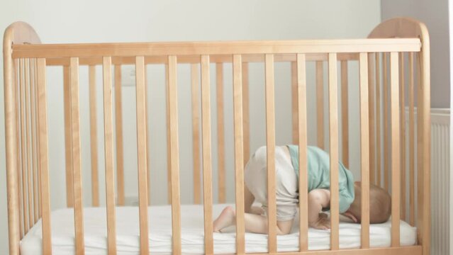 crying baby boy child kid lying in brown crib cot rolling, crawling, trying to sleep. caucasian toddler doesn't want or falling asleep, alone in cradle. childhood, parenthood, lonely getting to sleep 