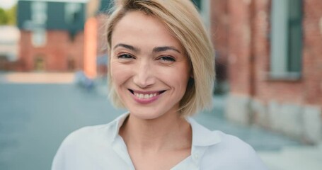 Close up portrait blond young attractive smile woman look at camera at city street. Outdoor portrait happy female girl. - Powered by Adobe