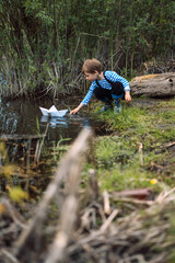 children launch paper boats into the pond on a rainy summer