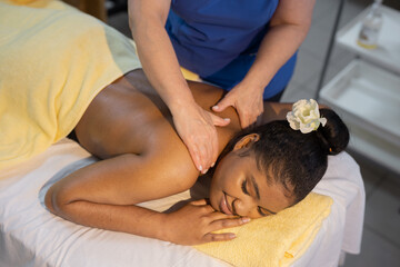 relaxation of beautiful african young woman at specialist on back massage	