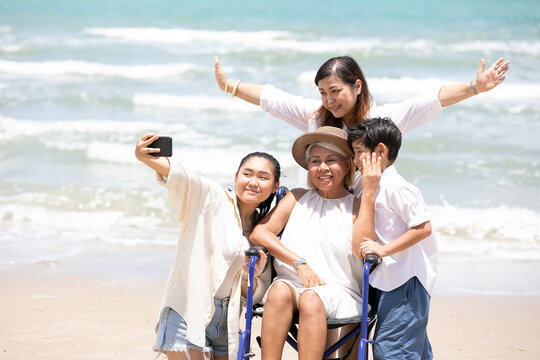 disabled woman in a wheelchair with family, selfie or taking photo together on the beach