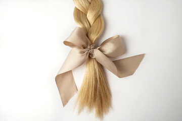 A blonde tress with a beige bow on a white background