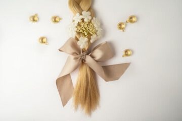 A blonde tress with a beige bow and oil vitamins for hair