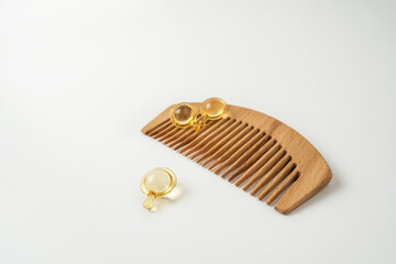 Natural oil vitamins golden capsules for hair lying on a wooden comb