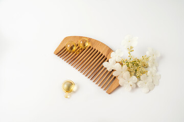 Natural oil vitamins golden capsules for hair lying on a wooden comb
