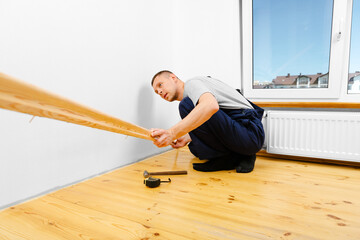 To make repairs. Installing a new skirting board. a man makes repairs in a room