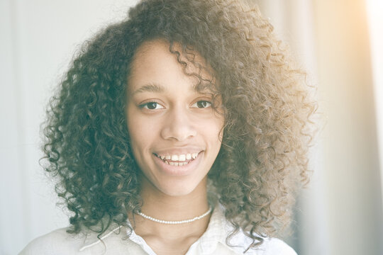 Portrait of a beautiful young woman with black curly hair. African american girl smiling. People, lifestyle, beauty concept  