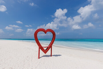Romantic symbol of red heart statue on the sand beach. Honeymoon destination, love romance concept, beach vacation
