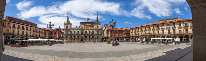 Panorámica de la plaza del ayuntamiento de estilo barroco en León con dos torres, en una plaza con farolas y edificios, con un cielo azul y alguna nube en verano de 2021