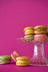 Sweet pastel colorful macaroons on hot pink background. Copy space