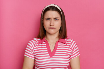 Portrait of scared nervous young Caucasian woman wearing striped T-shirt and hair band posing...