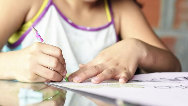 close-up of a brown-skinned latina girl, coloring her homework with a green pencil, low-income colombian student concentrating on her drawing. poverty and overcoming poverty concept