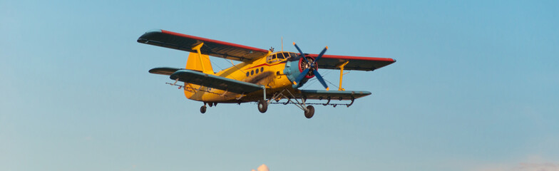 Agricultural airplane spraying pesticides on agricultural fields in summer