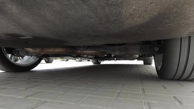View of the car suspension while driving. Wheels spinning under the car. Movement of a suspension bracket and shock-absorbers.