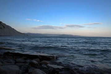 Coast of the Black Sea at sunset. Summer late evening. Beautiful seascape. Blue sky, steep cliffs, endless sea. Panoramic view. Russia.