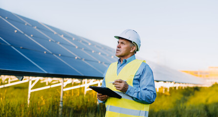 Portrait of engineer working with digital tablet at solar farm. Alternative Eco energy concept