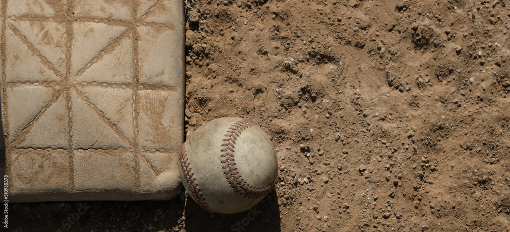 Wall mural baseball ball by base on dirt sports field close up, copy space on banner background. - Wall murals