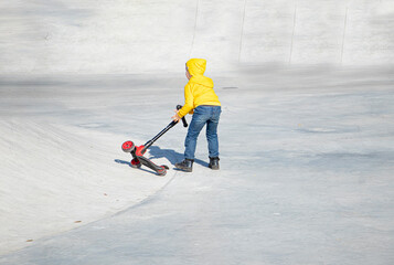 a child rides and fell from Kick scooter. playground for riding on Kick scooter. large concrete area for training on a scooter and skates. High quality photo