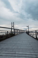Wooden pier with a bridge on a cloudy day with clouds