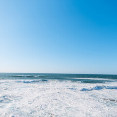 Fototapeta na wymiar Amazing clear Atlantic Sea with blue skies and waves. Journey to Portugal. Summer vacation at sea