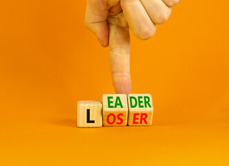 Loser or leader symbol. Concept words Loser or leader on wooden cubes. Businessman hand. Beautiful orange table orange background. Business and loser or leader concept. Copy space.