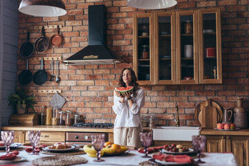 Woman at home eating watermelon in the kitchen