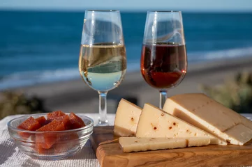 Fotobehang Spanish hard Andalusian cheese filled with sweet sherry served outdoor with membrillo jam with two glasses of sherry wine with beach and blue sea on background © barmalini
