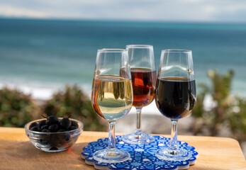 Tasting of Spanish sweet and dry fortified Vino de Jerez sherry wine and green olives with view on blue sea near El Puerto de Santa Maria, Andalusia, Spain