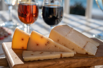 Spanish hard Andalusian cheese filled with Pedro Ximenez sweet sherry served outdoor with two glasses of sherry wine with blue sea on background