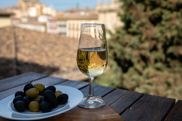 Tasting of Spanish sweet and dry fortified Vino de Jerez sherry wine and olives with view on roofs and houses of old andalusian town
