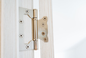 Obraz premium The hinge of the door is shot close-up, steel hinges are attached to the jamb of the doorway, cross-shaped screws are screwed into the door, interior details.