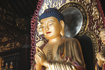 golden statue of buddha with a buddhist symbol on its chest