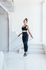 Fit woman with jump rope at home doing skipping workout.