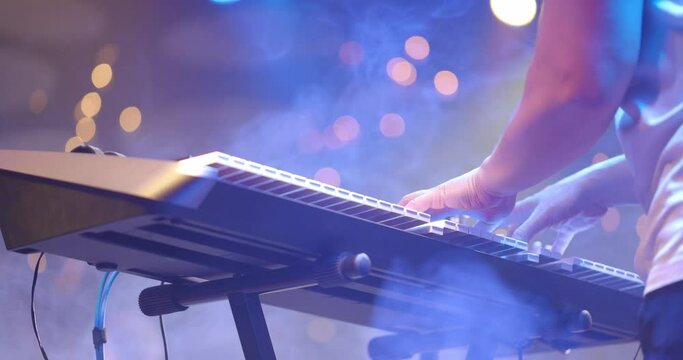Close up view of musician hands playing synthesizer piano on live concert at stage. The musician playing the electric piano
