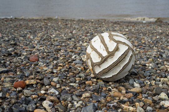 Old football washed up on a stony beach