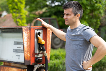 Man standing beside gasoline pump out of service