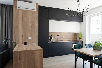 Modern kitchen interior with stylish furniture with wooden counter, window, table and chairs in...