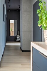 Corridor with mirror, wooden floor and grey door. Interior of hallway with entrance in stylish new apartment. White wall in building at home. Vertical.