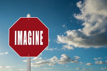 Red stop sign with the word Imagine on a blue sky background.