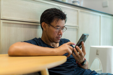 Man sit down and using mobile and social media. Man playing on him Smart phone