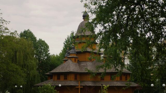 Ground view of the church of the Intercession of the Blessed Virgin in Ternopil, Ukraine. Old authentic Christian wooden church in middle of green trees. Cultural religious heritage building
