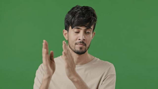Arab indian brunet man hispanic millennial guy approvingly nods head applauds close up male portrait clap hands say wow congratulate admiration gesticulation body language stands over green background