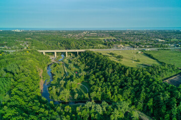 Drone shot of a bridge going over a valley in the summer