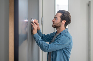 Man touching small appliance on wall with fingers