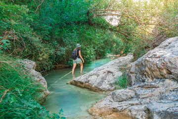 Young happy woman walking in turquoise blue crystal clear water in the river summer vacation relaxing body and mind.