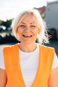 Close Up Portrait Of Worker Engineer Woman With Orange Vest. Female Truck Driver 