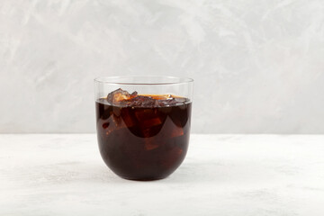 Cold iced coffee cocktail in clear glass. Refreshing summer alcoholic drink. Grey background, copy space