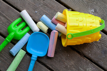 Children sand bucket holding colourful chalks and toy shovel spreading on floor. Children play scene.